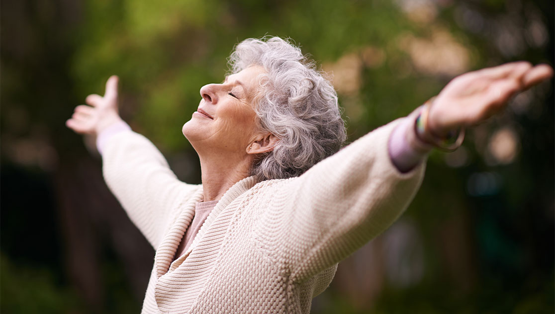 senior woman with arms out and face to the sky